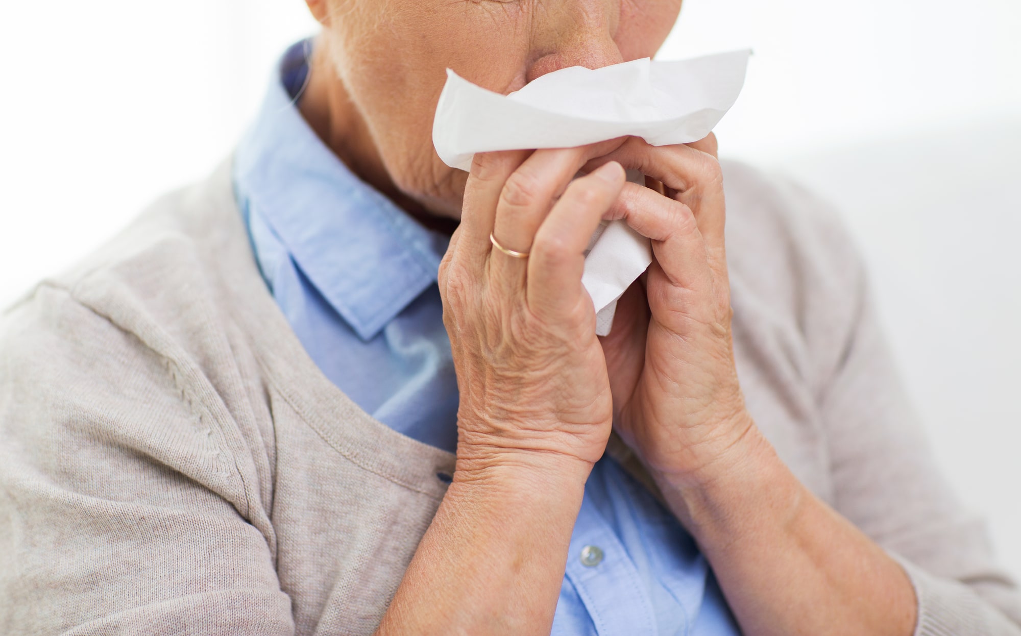 A sick person uses a tissues to blow their nose. Runny nose can be a symptom of prolonged exposure to mold.