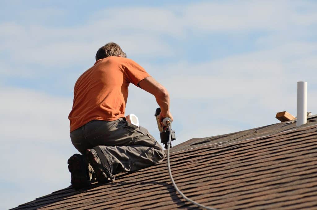 man on roof with nail gun