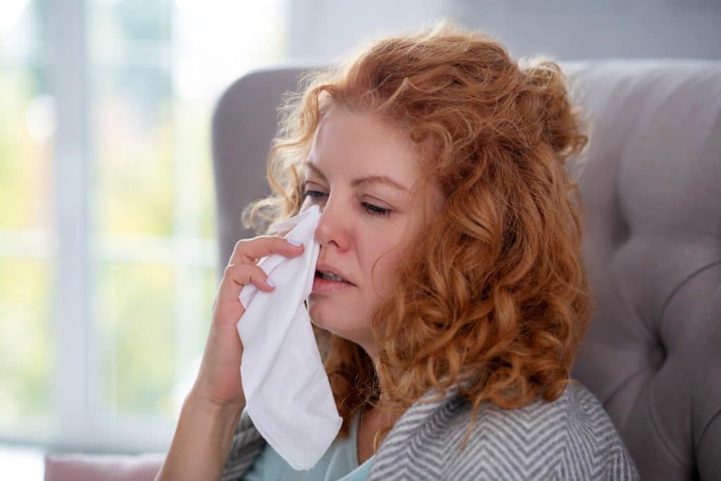 Young woman wiping nose with tissue
